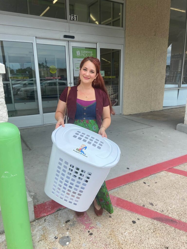 Melanie carrying a white Project Linus donation basket outside a shop